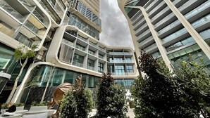 A modern building with a curved facade, multiple balconies, and a central atrium with glass walls.