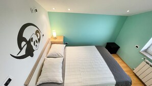 Une chambre à coucher comprenant un lit, une table de chevet, une horloge murale et un luminaire fixé au mur.