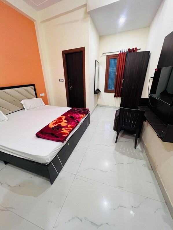 A bedroom with a bed, a desk, a chair, a TV, and a wardrobe.