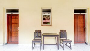 Une pièce avec deux portes en bois, une fenêtre avec des rideaux et une table avec deux chaises.