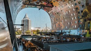 Vue intérieure d’un bâtiment moderne doté d’une façade en verre incurvée, d’un atrium central et d’une vue sur un autre bâtiment situé au loin.