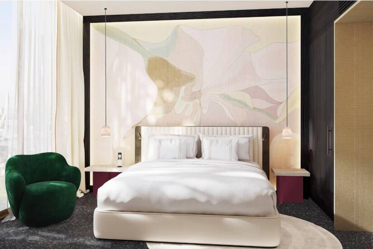 A modern bedroom with a large bed, a green armchair, and a decorative wall.