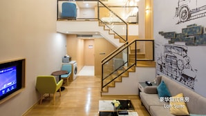 Una suite tipo loft con escalera, un sofá, una mesa de centro, un televisor y una lavadora.