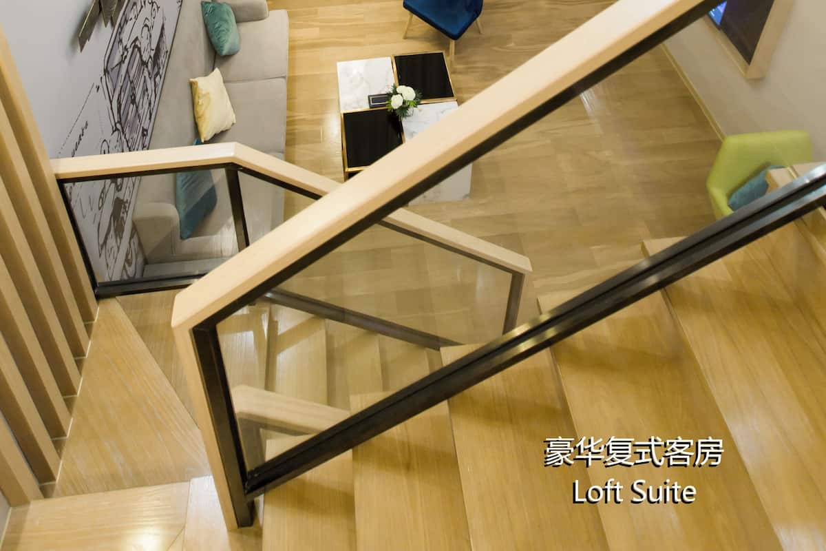 Un suite loft modern amb escala, un sofà, una cadira blava i una televisió penjada a la paret.