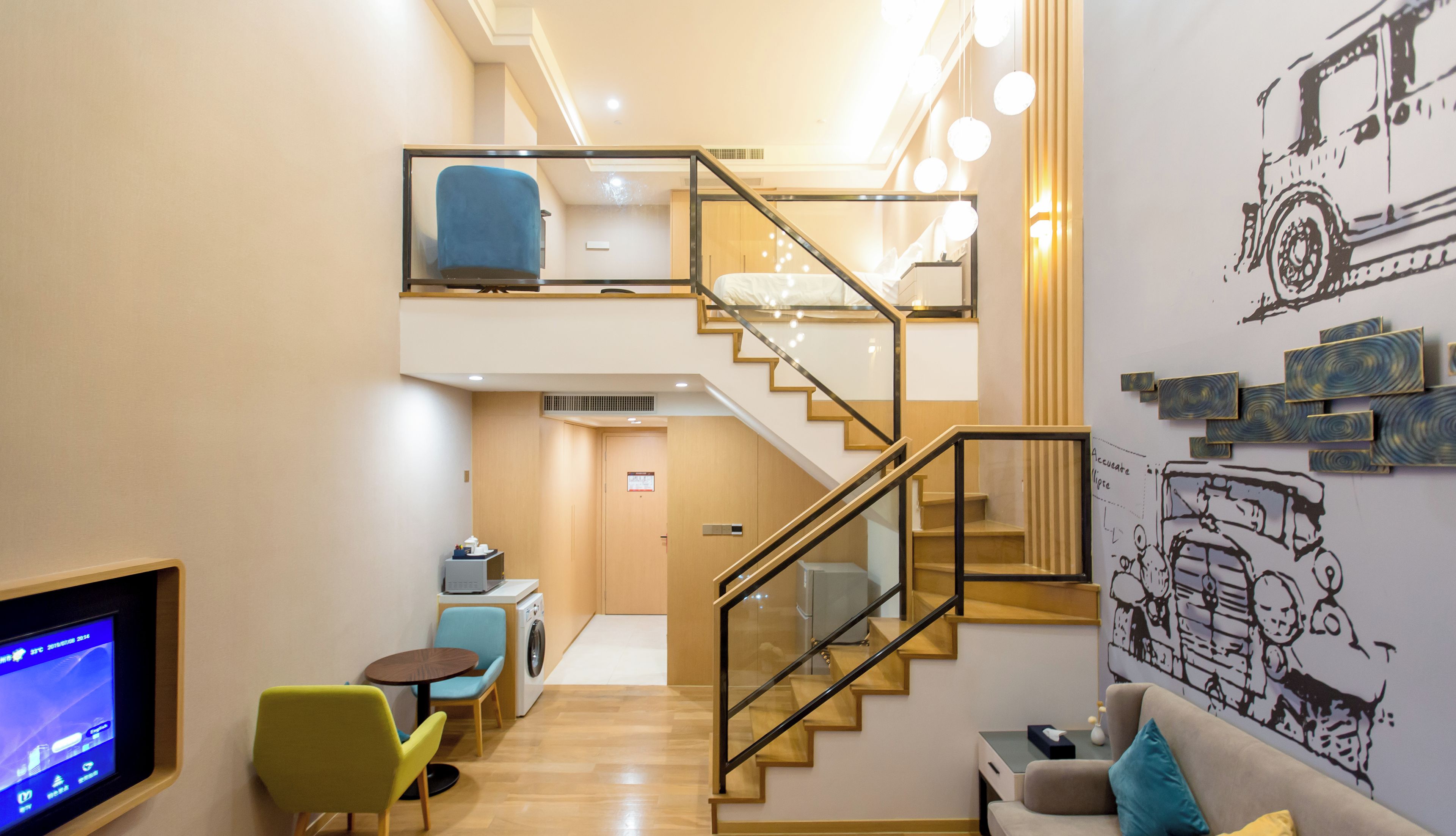 Una suite tipo loft con escalera, un sofá, una mesa de centro, un televisor y una lavadora.