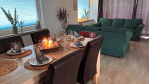 A dining area with a wooden table set for four, surrounded by dark leather chairs. - Haus 53° Nord - North Sea vacation for the whole family - pets welcome (Südbrookmerland)