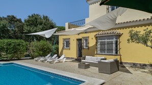 A poolside area with lounge chairs, a sofa, and a covered seating area.