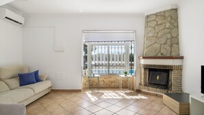 A living room with a sofa, a fireplace, a TV, and a view of a pool.