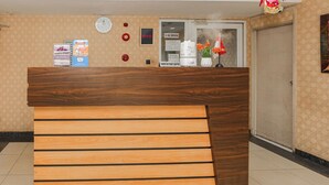 A reception desk with a wooden finish, a clock, a 'No Smoking' sign, and a framed picture on the wall. - Capital O 94796 Apartment Mutiara Bekasi (Bekasi)