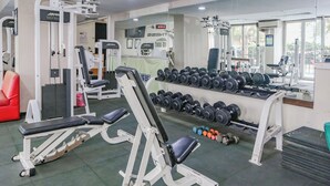 A gym with weightlifting equipment, dumbbells, and cardio machines. - Capital O 94796 Apartment Mutiara Bekasi (Bekasi)