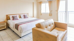 A hotel room with a bed, a sofa, a nightstand, and a window with curtains. - Capital O 94796 Apartment Mutiara Bekasi (Bekasi)