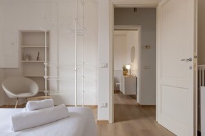Une chambre d’hôtel avec un lit, une chaise, une armoire et un bureau avec une lampe.