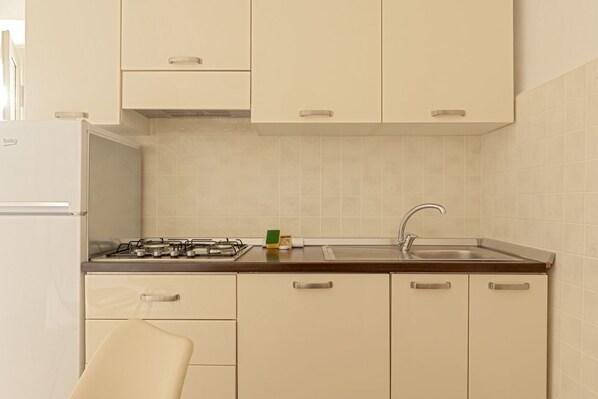 A kitchen with white cabinets, a stove, and a sink.