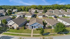 A residential neighborhood with single-family homes, well-maintained lawns, and a clear sky.