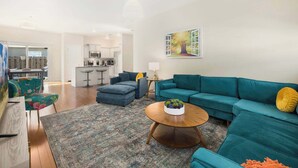 A modern living room with teal sofas, a round coffee table, and a patterned rug.