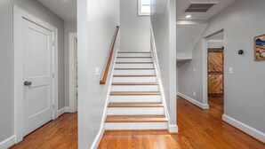 Una escalera de madera con paredes blancas que lleva a otra habitación.