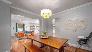 Un comedor con una mesa de madera y bancos, una lámpara colgante y adornos de macramé en las paredes.