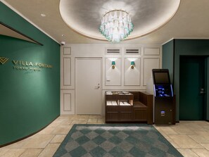 A lobby with a green wall, a chandelier, a reception desk, and a digital kiosk. - Hotel Villa Fontaine Tokyo Hibiya (Tokyo)