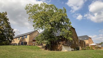 A building with a sloped roof, a large tree in front, and a grassy area.