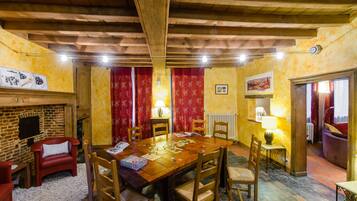 Un'accogliente zona pranzo con un tavolo in legno, sedie rosse e un camino.