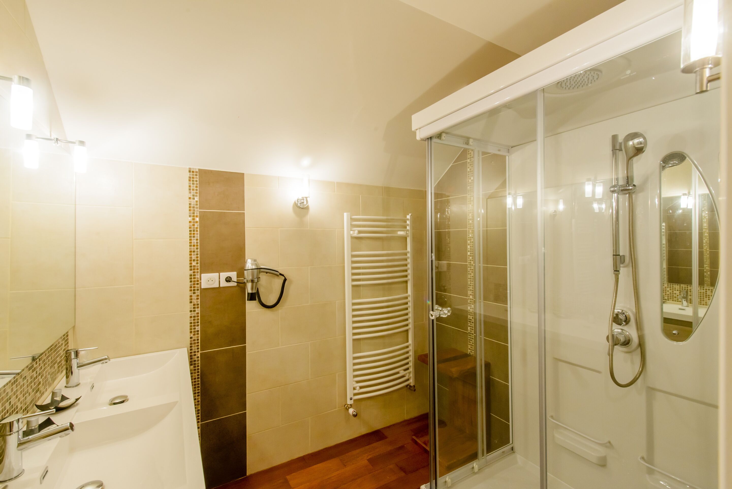 A modern bathroom with a glass-enclosed shower, a white sink, and a towel rack.