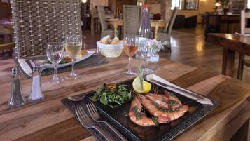 Een eettafel met een zeevruchtengerecht, wijnglazen en bestek.