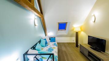 A bedroom with a bed, a TV, a lamp, and a small window.