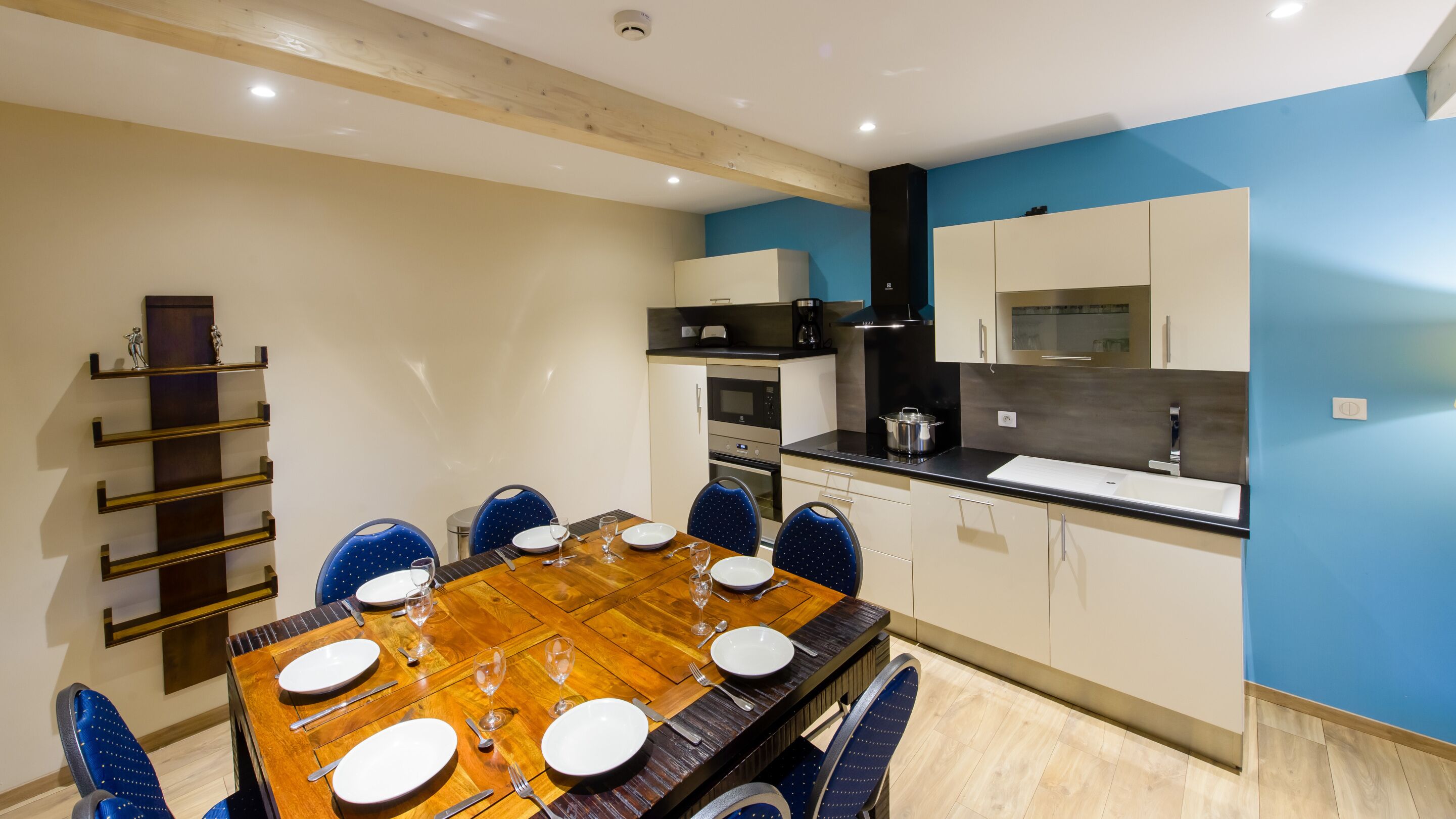 A dining area with a wooden table set for six, surrounded by blue chairs.