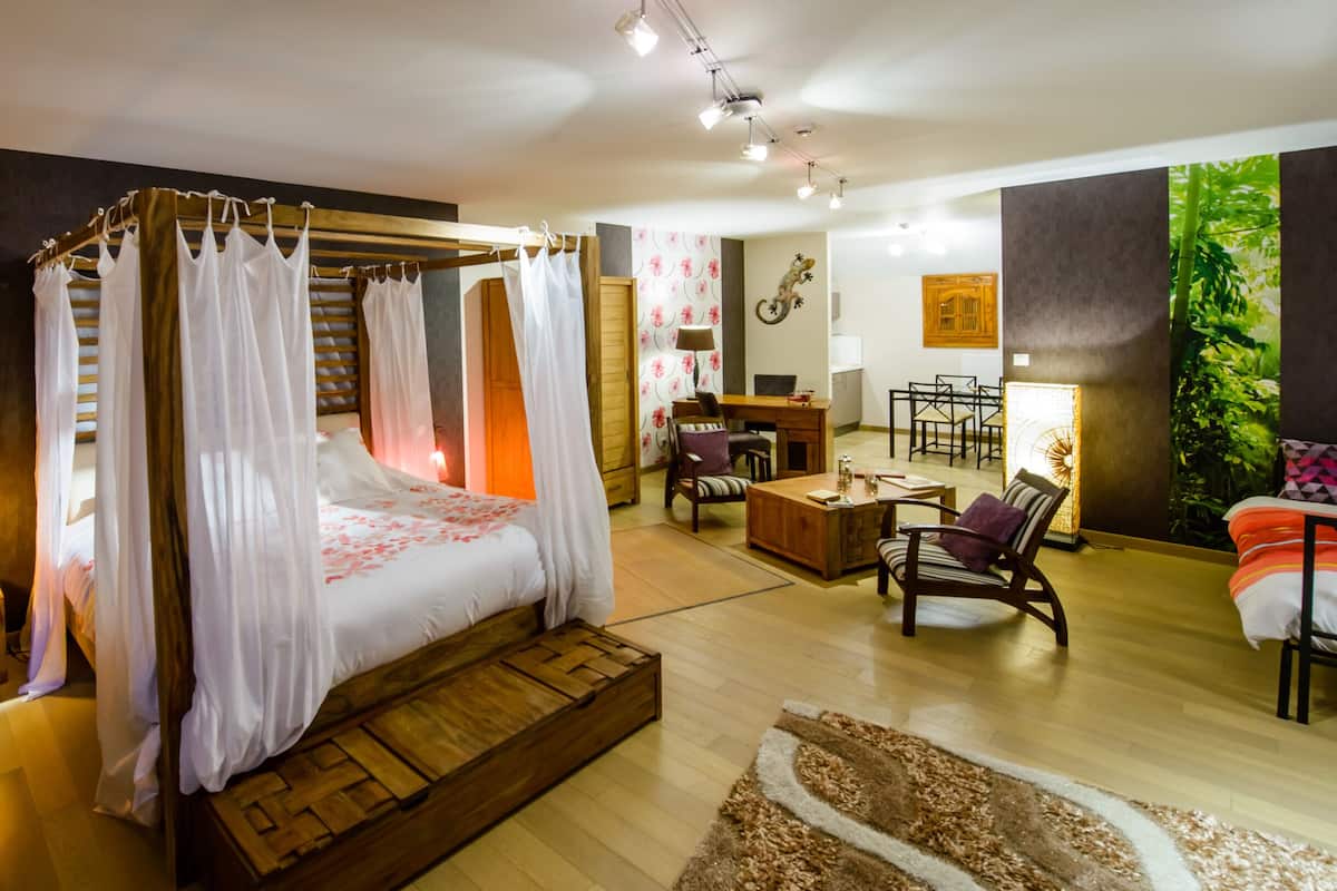 Une chambre spacieuse avec un lit à baldaquin, une table de chevet en bois, un bureau et une chaise.