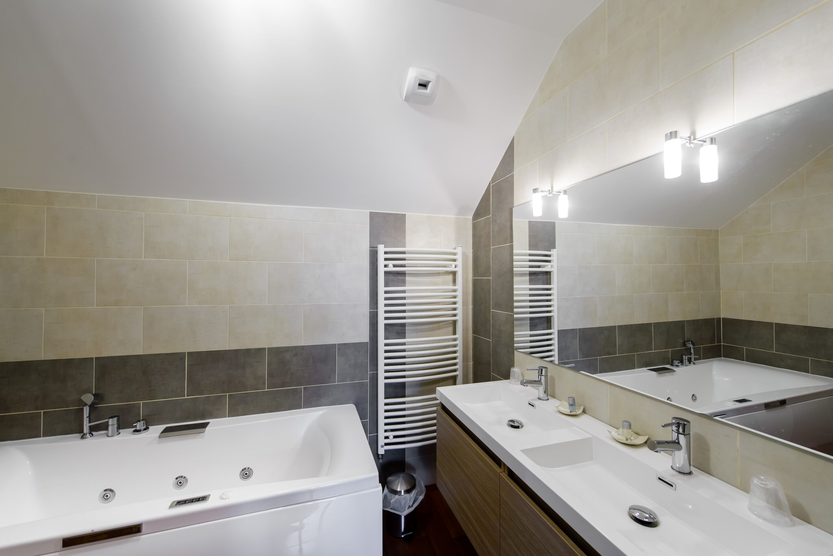 Une salle de bain moderne avec une grande baignoire, deux lavabos et un miroir.