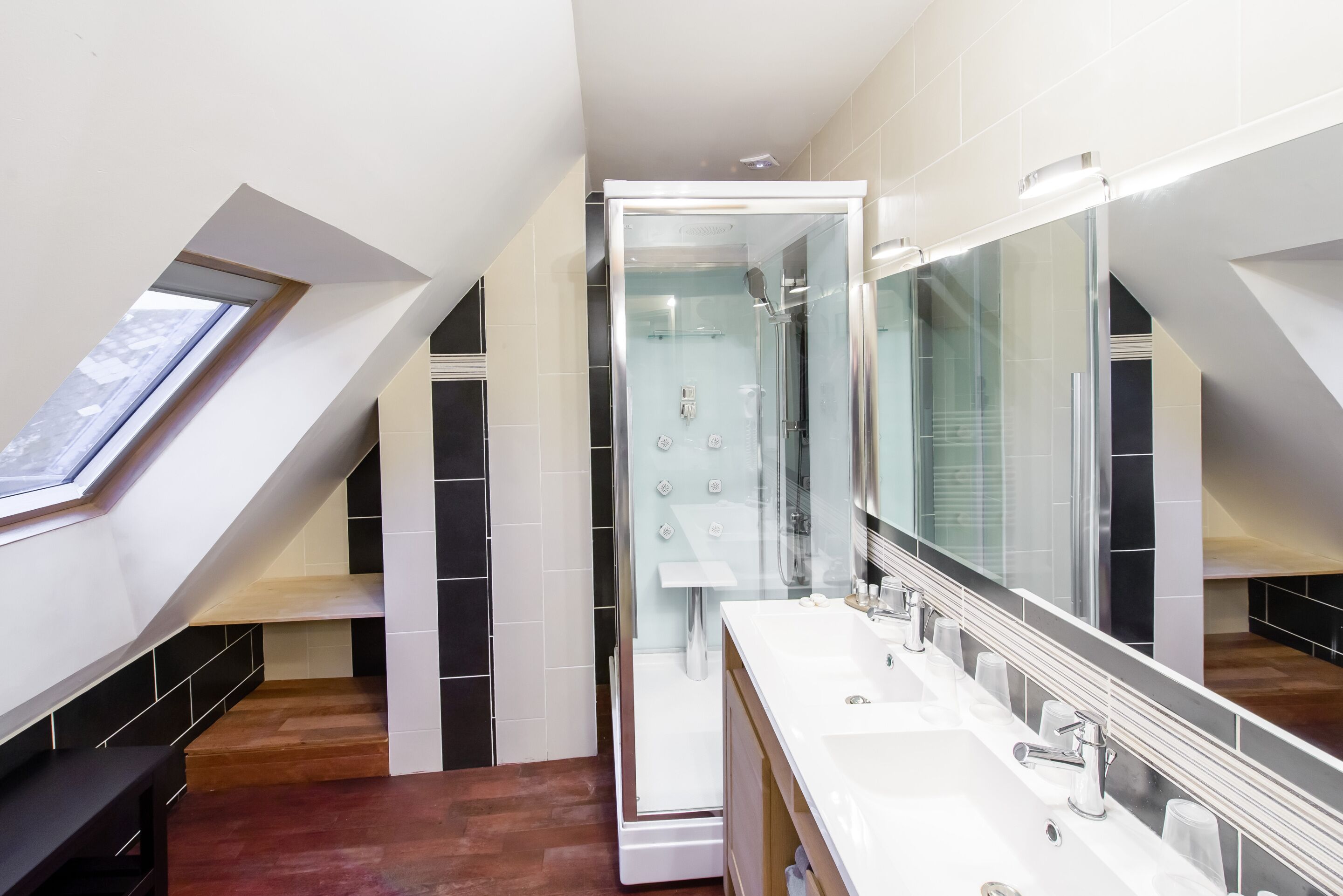 Une salle de bain moderne dotée d’un puits de lumière, d’une douche à l’italienne et d’un grand miroir.