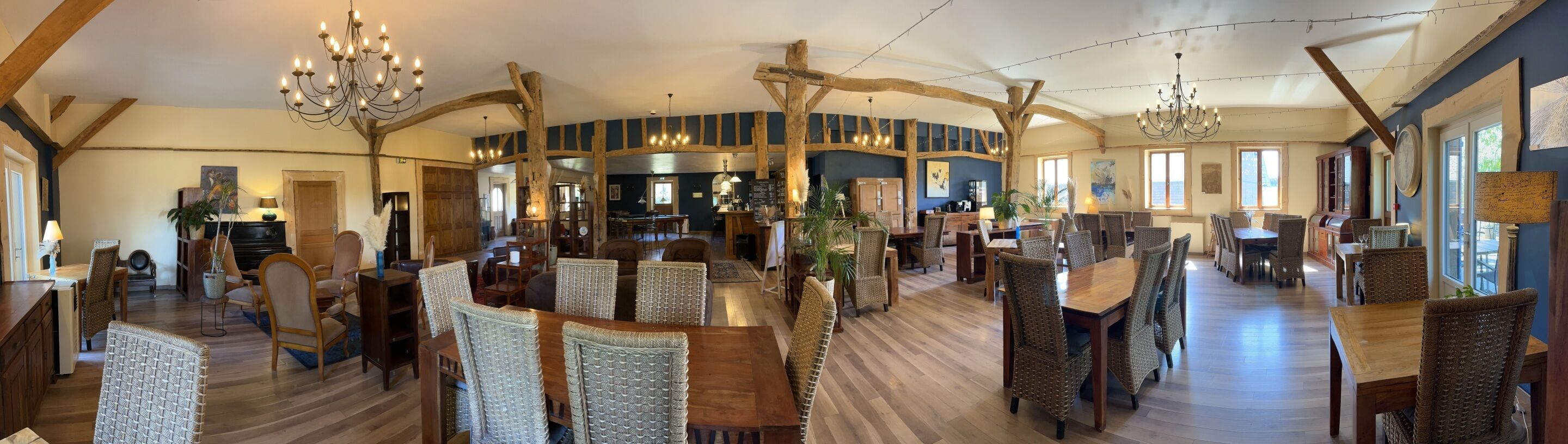 Un intérieur spacieux et rustique, avec de hauts plafonds, des poutres apparentes et plusieurs coins salon.