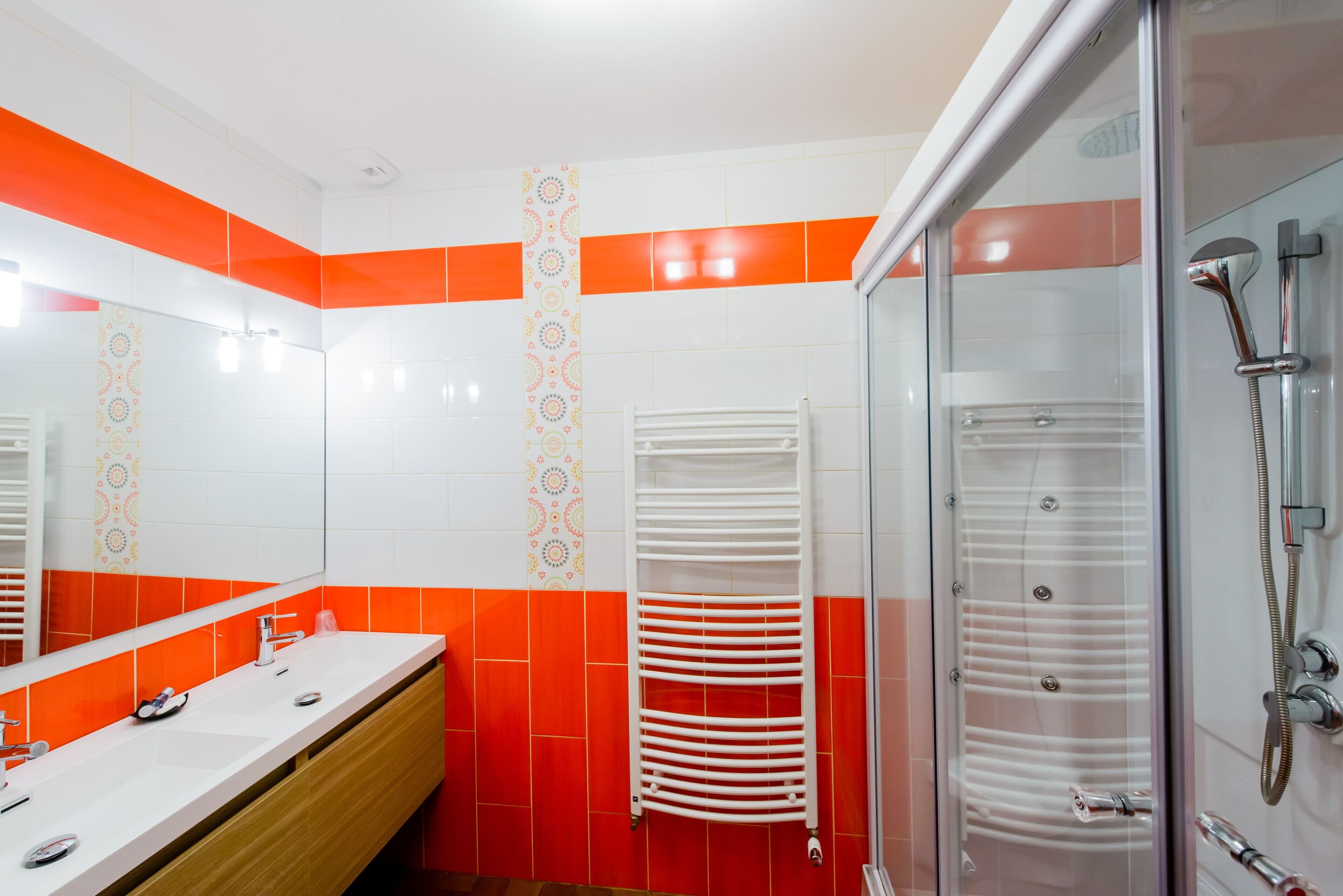 A bathroom with a white sink, a mirror, a towel rack, and a glass shower enclosure.