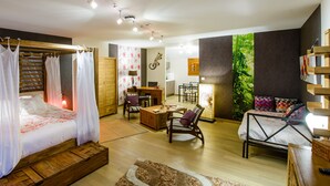 Un dormitorio con estructura de cama de madera, una mesita de noche, una silla, un escritorio y un sofá.
