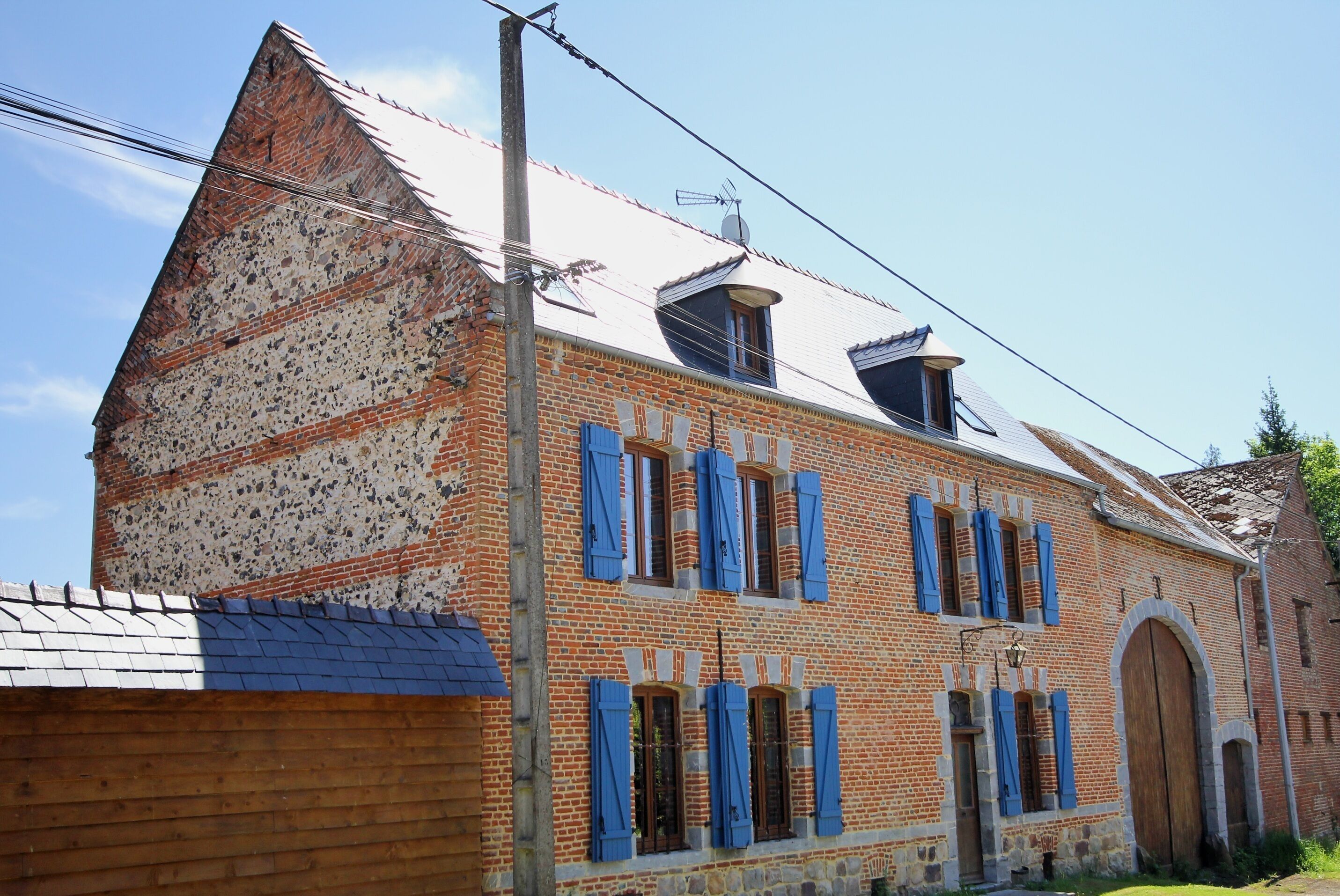 A traditional brick building with multiple windows, a large wooden door, and a sloped roof.