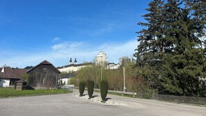 A street view with a large building in the background, a wooden barn, and a large tree on the right. - FarawayHomes Studios Kremsmünster (Kremsmuenster)