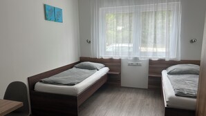 A small, modern room with two single beds, a desk, and a window with sheer curtains. - FarawayHomes Studios Kremsmünster (Kremsmuenster)