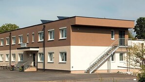 A modern building with a flat roof, multiple windows, and a staircase leading to an upper level.