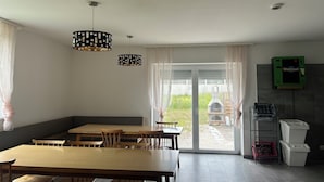 A dining area with a large wooden table and chairs, a fireplace, and a view of the outdoors.