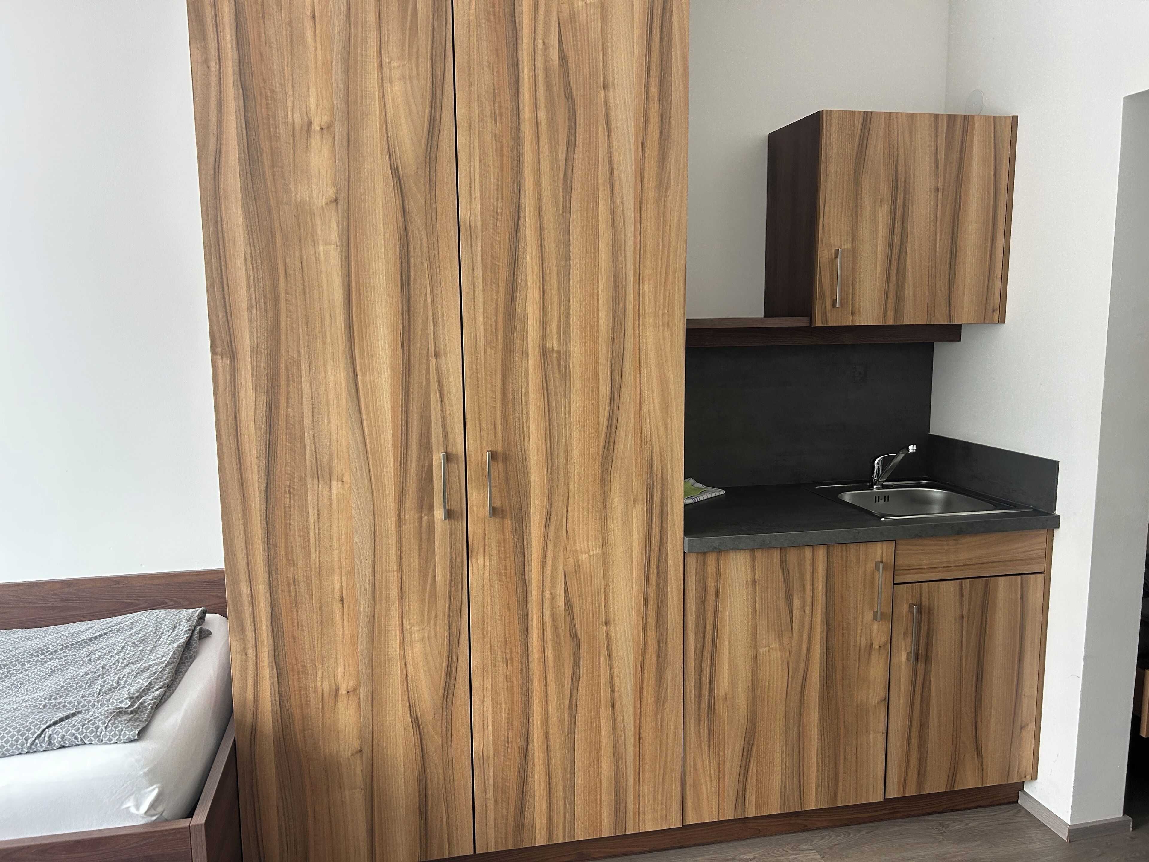 A compact kitchen with wooden cabinets and a black countertop.