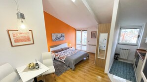 A modern bedroom with a bed, a desk, and a chair. There is a window and a door leading to a balcony. - App Villa Palma 2 (Rovinj)