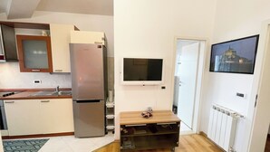 A compact kitchen with a refrigerator, a sink, and a microwave. There's a wooden cabinet and a television mounted on the wall. - App Villa Palma 2 (Rovinj)