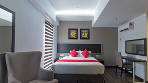 Moderni hotellihuone, jossa on suuri sänky, työpöytä, tuoli ja televisio.