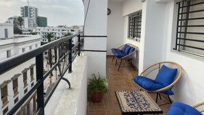 A balcony with two wicker chairs, a small table, and a potted plant. - Chic & Elegant Stay in Central Rabat (Rabat)