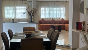 A modern dining area with a rectangular table, chairs, and a sofa in the background. - Chic & Elegant Stay in Central Rabat (Rabat)