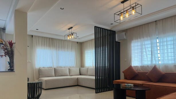 A modern living room with a sectional sofa, a smaller sofa, a coffee table, and a decorative vase. - Chic & Elegant Stay in Central Rabat (Rabat)