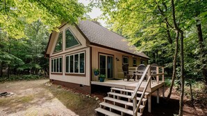 Een chalet met een terras, grote ramen en een trap naar de ingang.