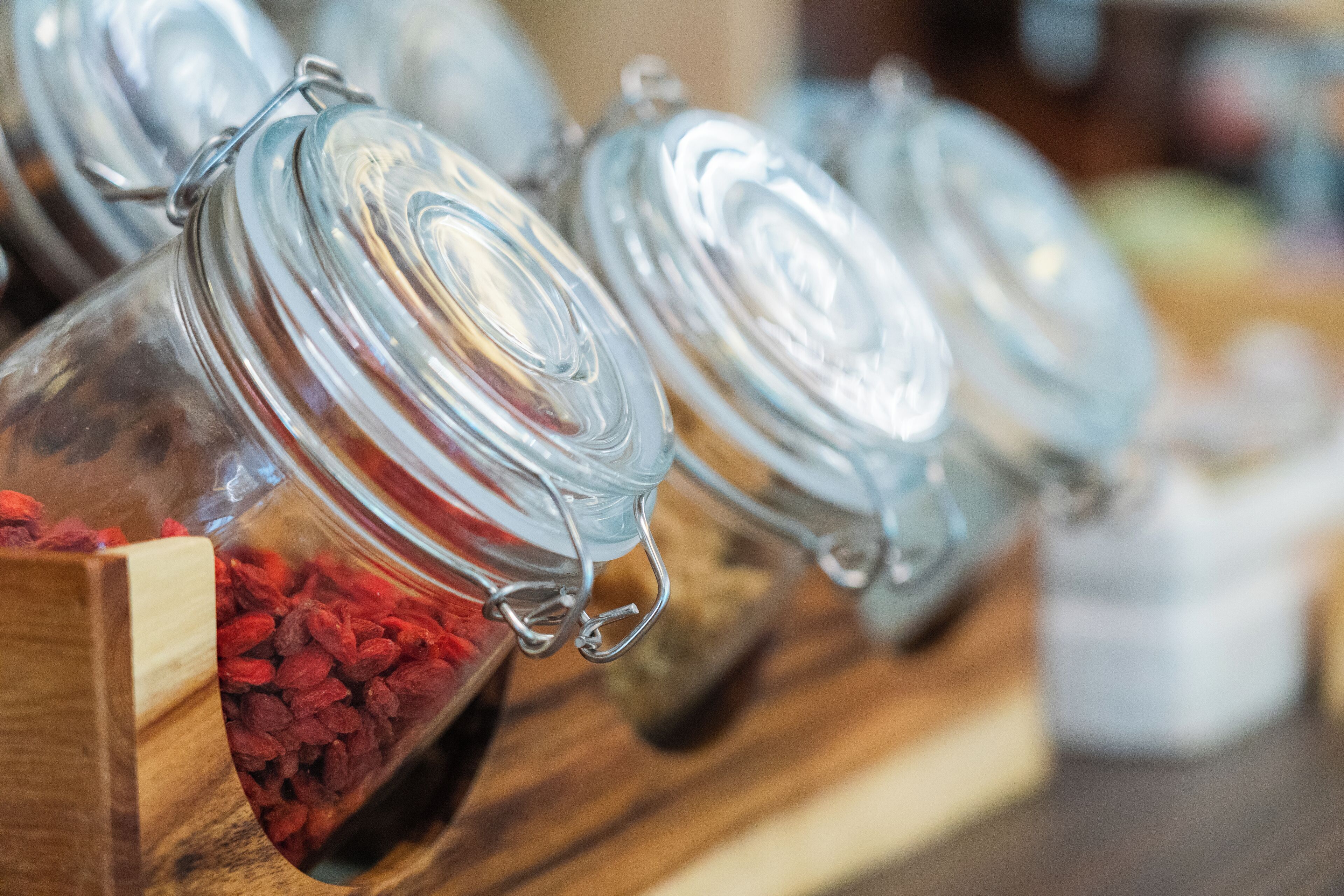 Glass jars with metal lids on a wooden shelf.