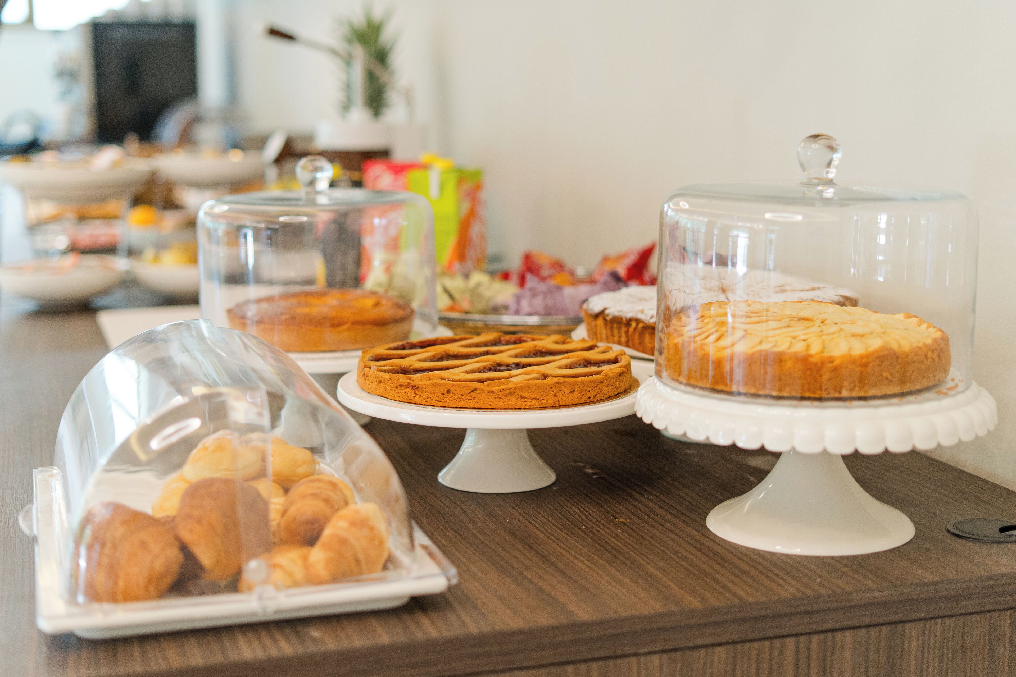 Une table de buffet présentant diverses pâtisseries, protégées par des cloches en verre.