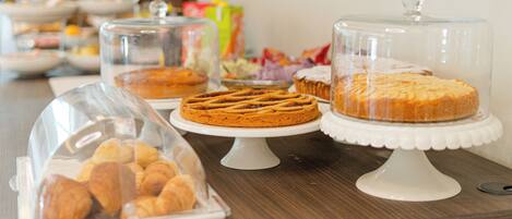 Une table de buffet présentant diverses pâtisseries, protégées par des cloches en verre.